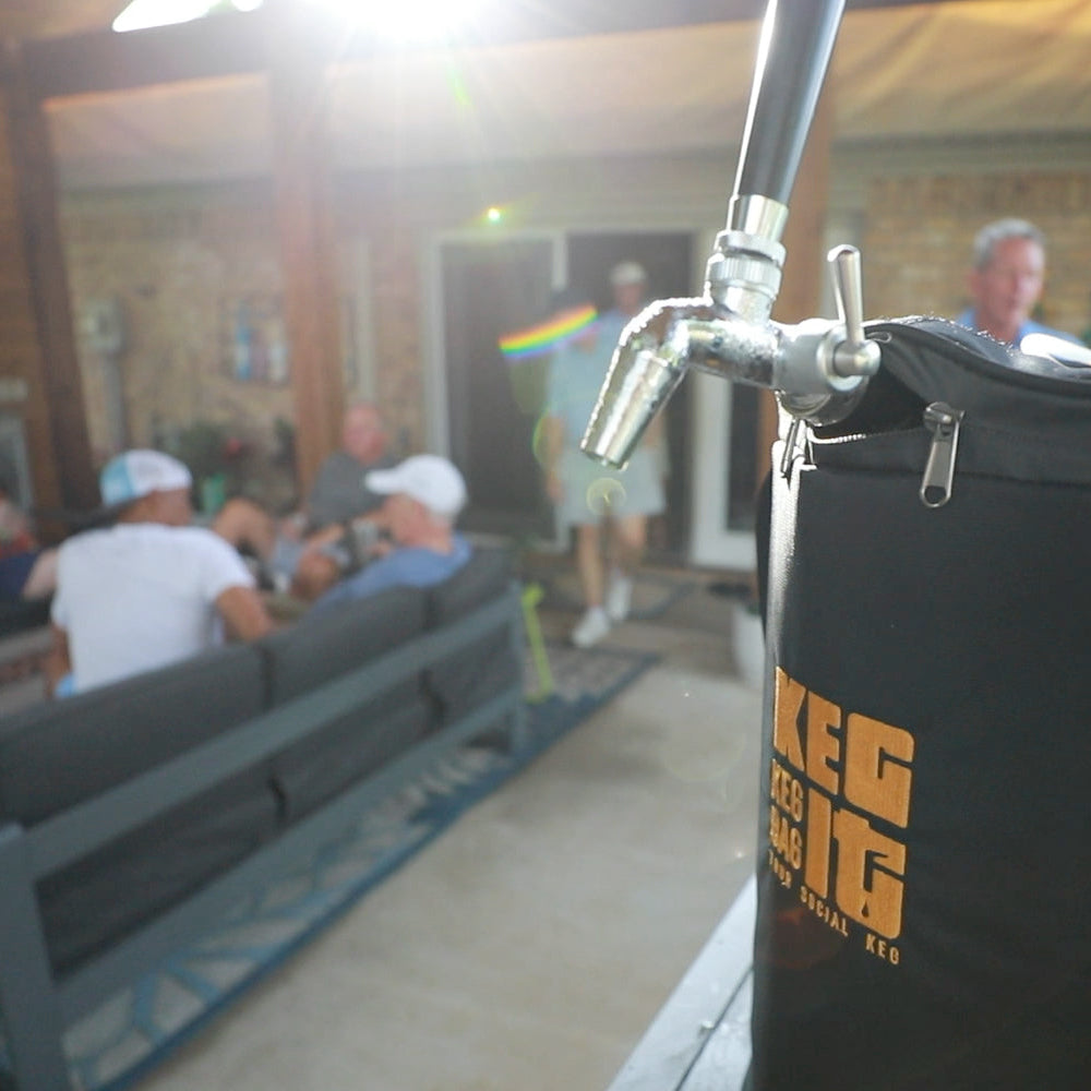 Keg It Keg Kit in the Black and Gold color scheme in the foreground in a covered patio setting with several friends in the background hanging out and having a good time.